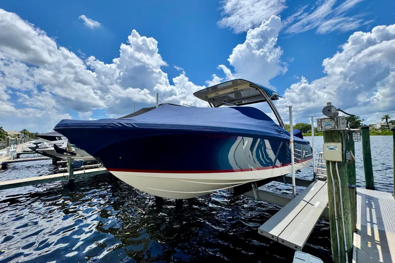 Slide: The Image of 2023 Chris-Craft Calypso 28 boat docked, covered, under a partly cloudy sky. - 34