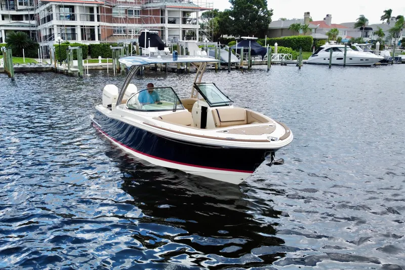 Slide: The Image of 2023 Chris-Craft Calypso 28 boat cruising in a marina with waterfront buildings. - 4