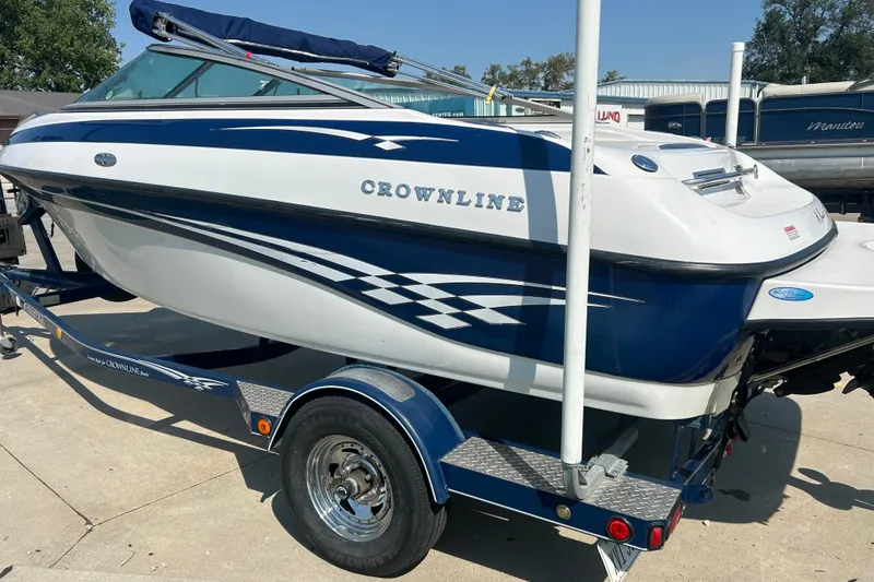 Slide: The Image of 2003 Crownline 192 BR boat on trailer, blue and white design, parked outdoors. - 2
