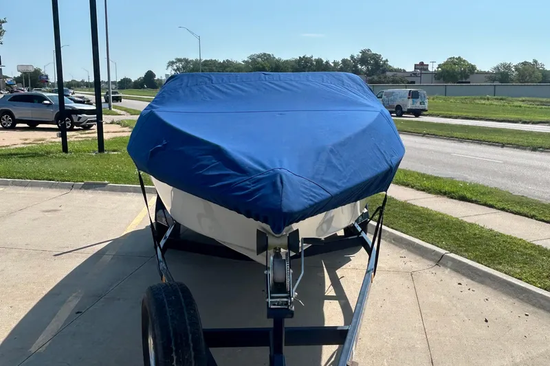 Slide: The Image of 2003 Crownline 192 BR boat with blue cover on trailer, parked in a lot. - 5