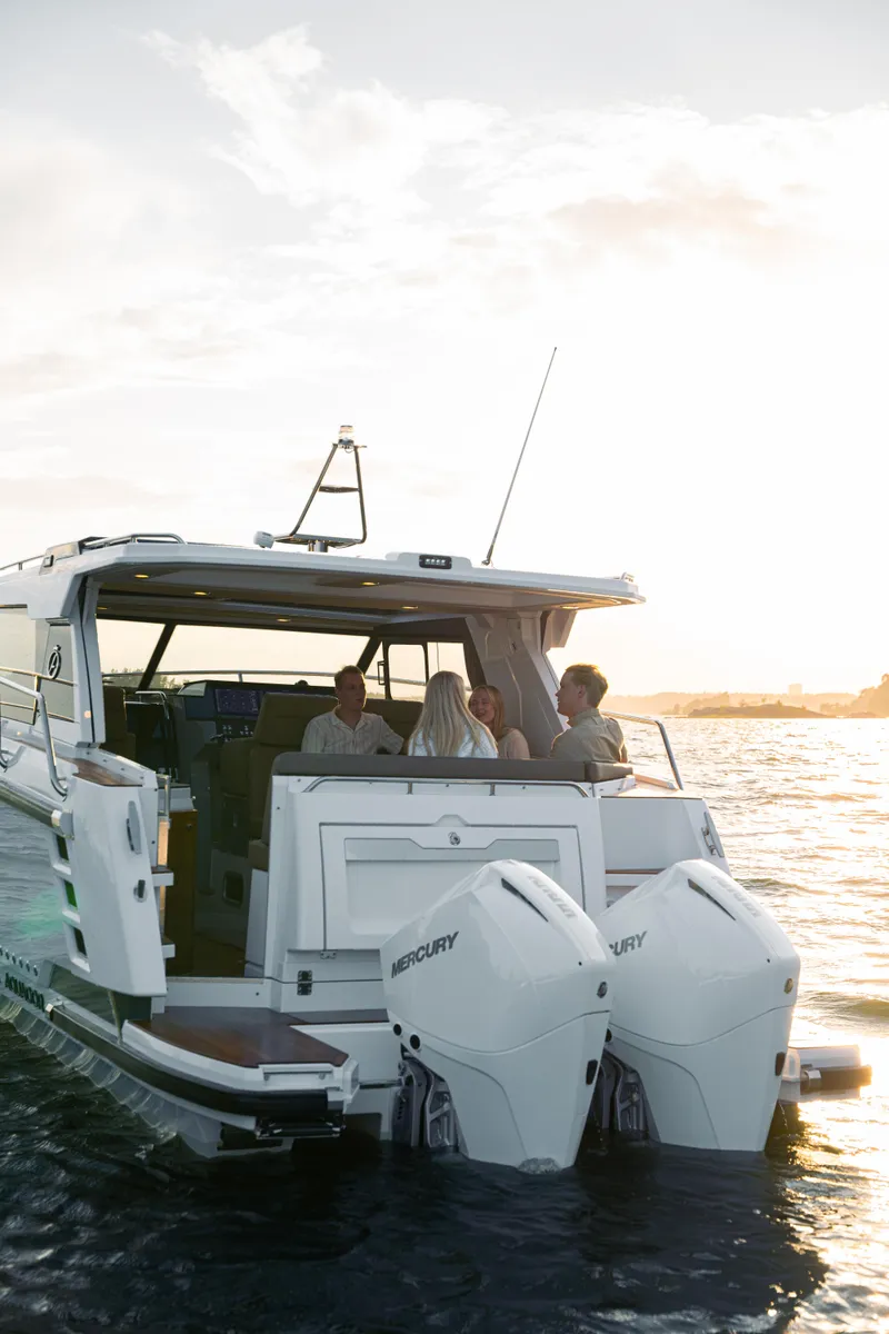 Slide: The Image of Aquador 300 HT 2025 boat cruising at sunset with passengers onboard. - 11