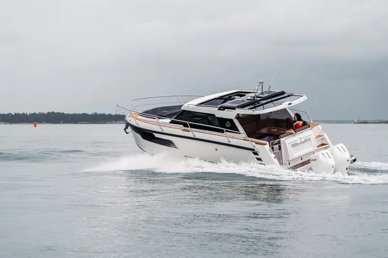 Slide: The Image of 2025 Aquador 300 HT cruising on open water under cloudy skies. - 12