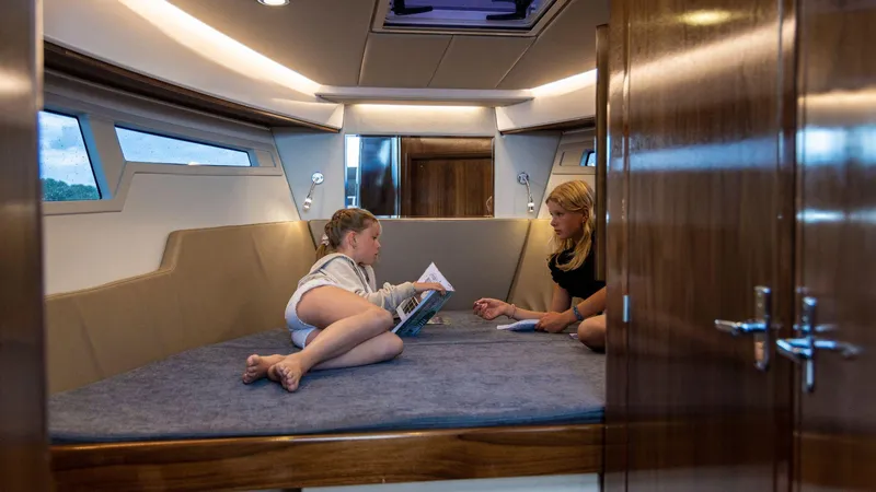 Slide: The Image of Interior of 2025 Aquador 300 HT yacht with two people relaxing on a bed. - 15