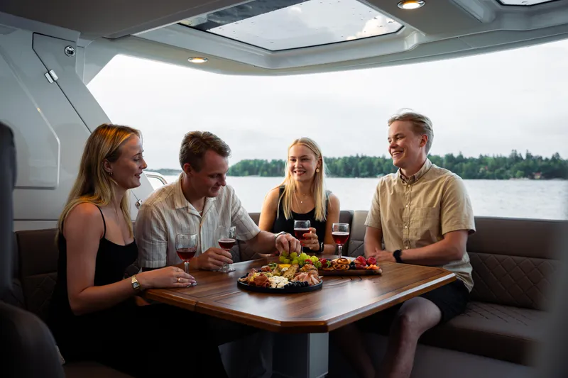 Slide: The Image of People enjoying a meal on a 2025 Aquador 300 HT boat, with a scenic water view. - 18