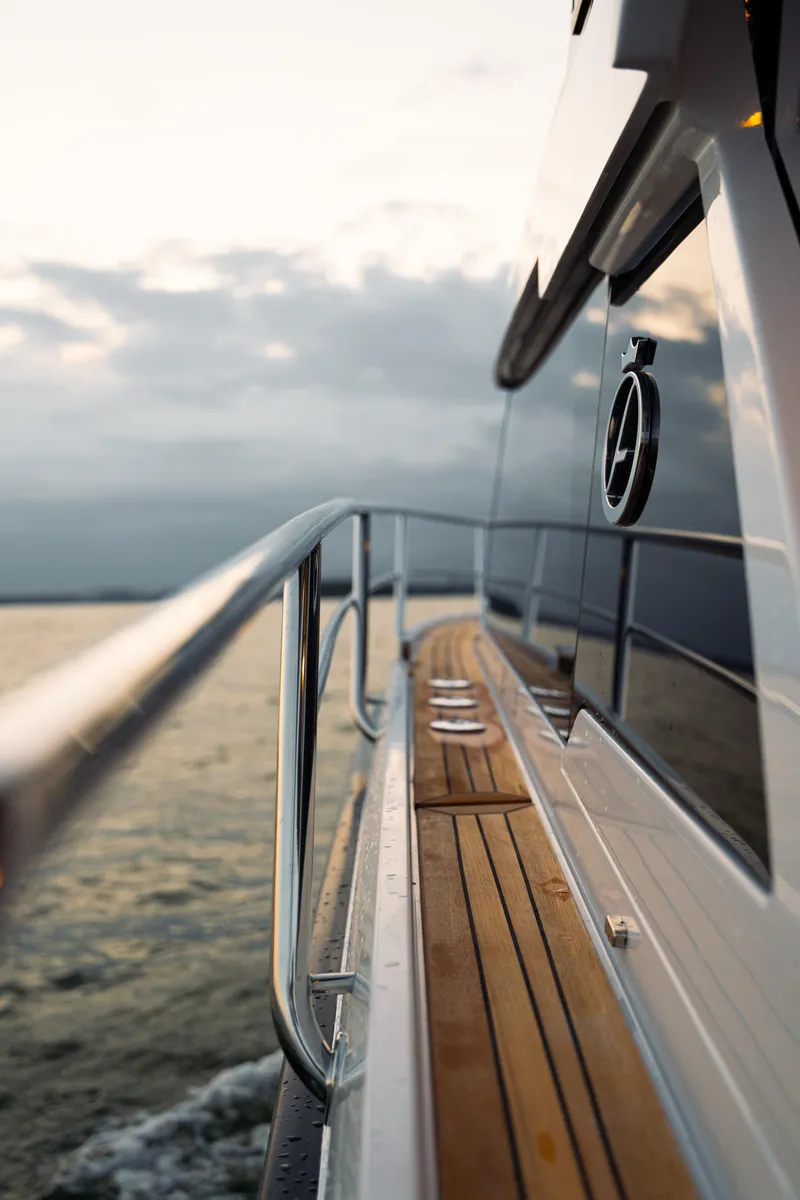 Slide: The Image of 2025 Aquador 300 HT yacht, sleek design, wooden deck, cruising on open water. - 19