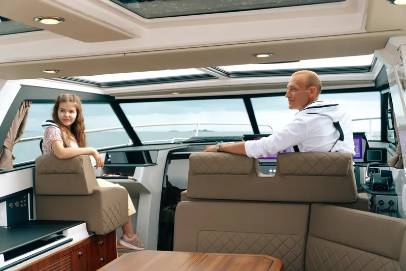 Slide: The Image of Interior of 2025 Aquador 300 HT boat with two people seated, enjoying the view. - 2