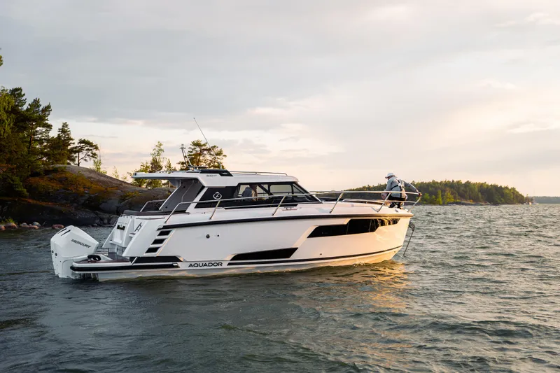 Slide: The Image of 2025 Aquador 300 HT boat cruising on a scenic lake at sunset. - 26