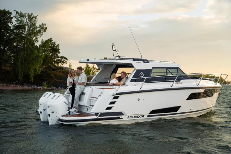 Slide: The Image of Aquador 300 HT 2025 motorboat cruising on a scenic lake with passengers onboard. - 27