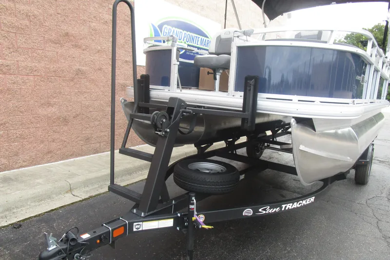 Slide: The Image of 2026 Sun Tracker Bass Buggy 18 DLX pontoon boat on trailer, parked outdoors. - 4