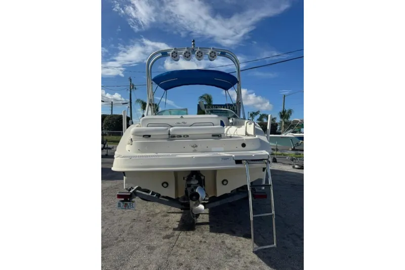 Slide: The Image of 2009 Sea Ray 230 Sundeck boat with blue canopy, rear view, parked outdoors. - 3