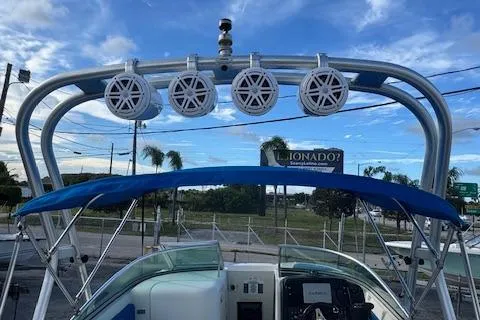 Slide: The Image of 2009 Sea Ray 230 Sundeck with speakers and blue canopy against a cloudy sky. - 34