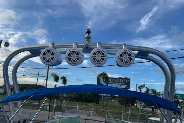 Slide: The Image of 2009 Sea Ray 230 Sundeck with speakers and blue canopy under a clear sky. - 35