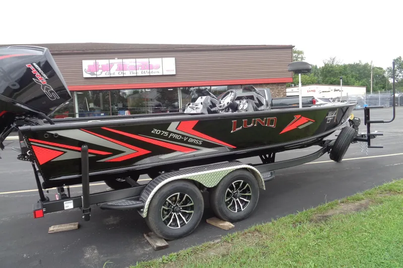 Slide: The Image of 2026 Lund 2075 Pro-V Bass XS boat with powerful outboard motor in parking lot. - 6