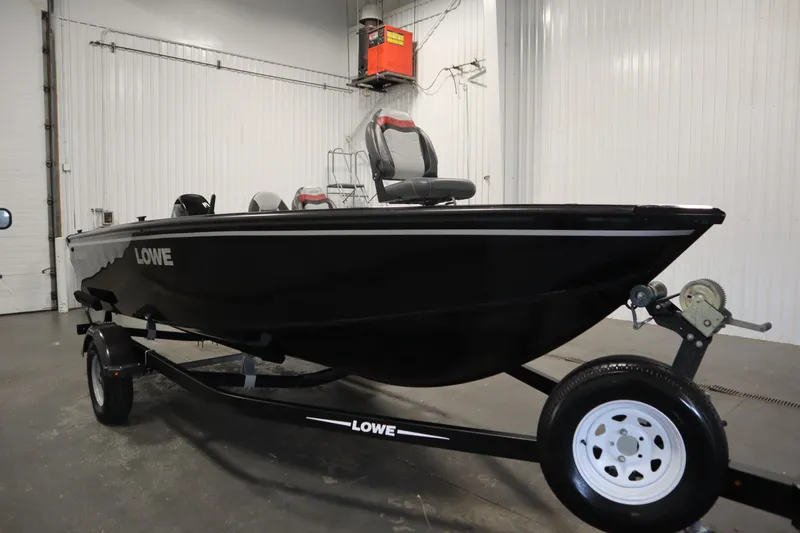 Slide: The Image of 2017 Lowe 1610 FM boat in a garage, black exterior, on a trailer. - 2