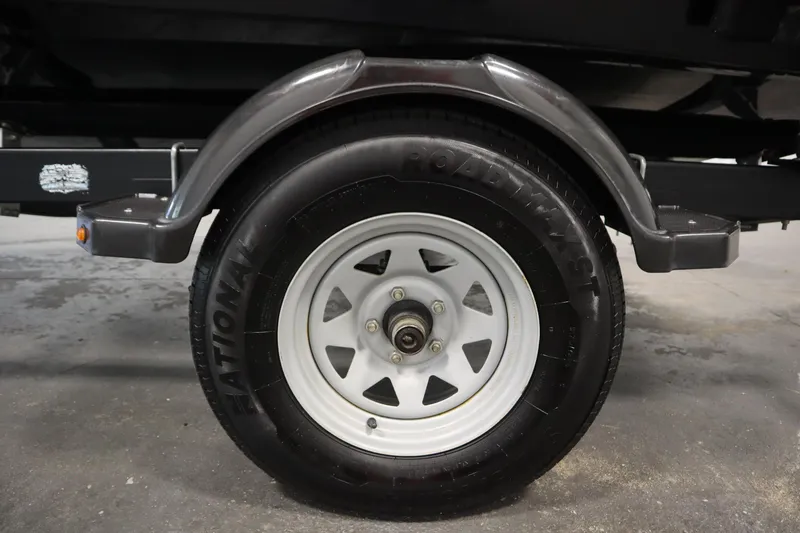 Slide: The Image of Close-up of a 2017 Lowe 1610 FM trailer wheel with black tire and white rim. - 44