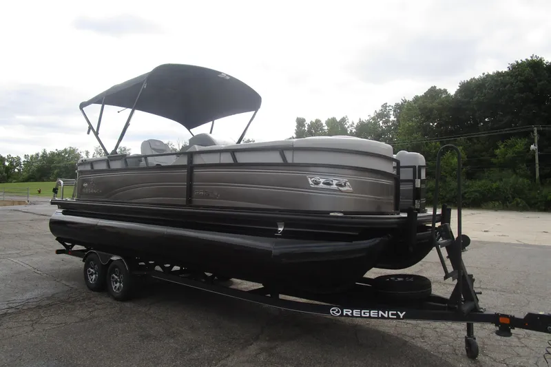 Slide: The Image of 2024 Regency 230 LE3 pontoon boat on trailer, parked outdoors. - 3