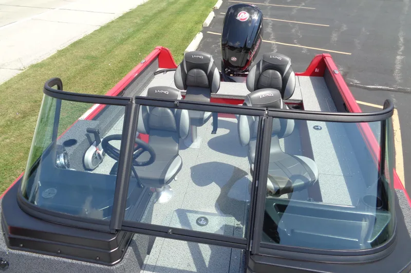 Slide: The Image of 2026 Lund 1800 Explorer Sport boat interior with seating and steering wheel, parked on pavement. - 22