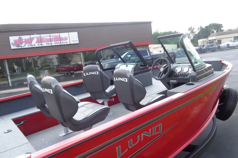 Slide: The Image of 2026 Lund 1800 Explorer Sport boat with seating, parked outside a marine store. - 8