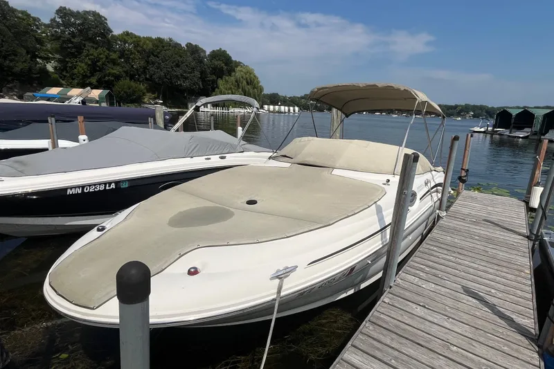 Slide: The Image of 2001 Sea Ray 240 Sundancer docked at a lakeside marina under a clear sky. - 1