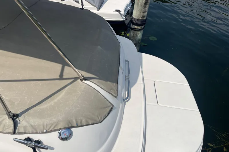 Slide: The Image of 2001 Sea Ray 240 Sundancer boat docked, featuring a covered deck and water view. - 11