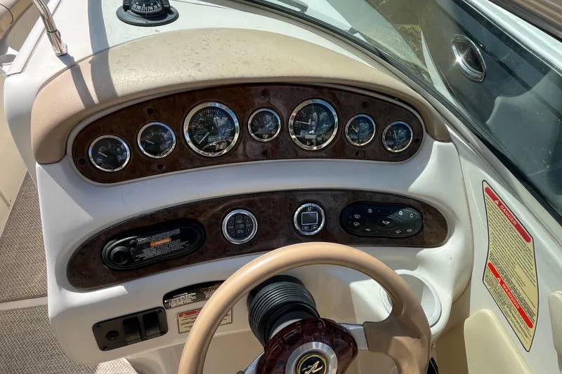 Slide: The Image of 2001 Sea Ray 240 Sundancer dashboard with gauges and controls, featuring a beige steering wheel. - 23