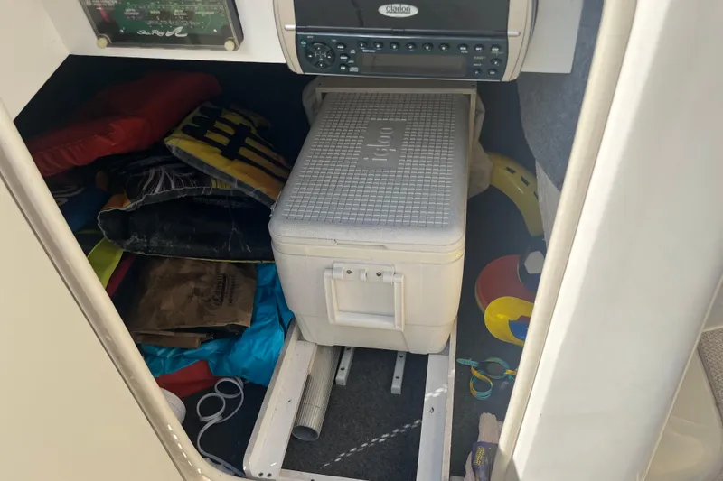 Slide: The Image of 2001 Sea Ray 240 Sundancer cabin storage with cooler, life jackets, and boating accessories. - 25