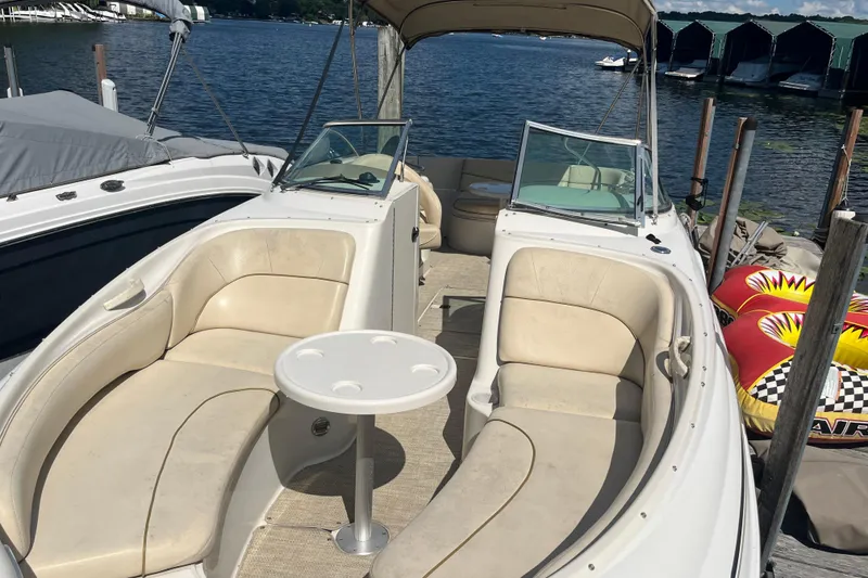 Slide: The Image of 2001 Sea Ray 240 Sundancer boat with beige seating and table, docked by the lake. - 5