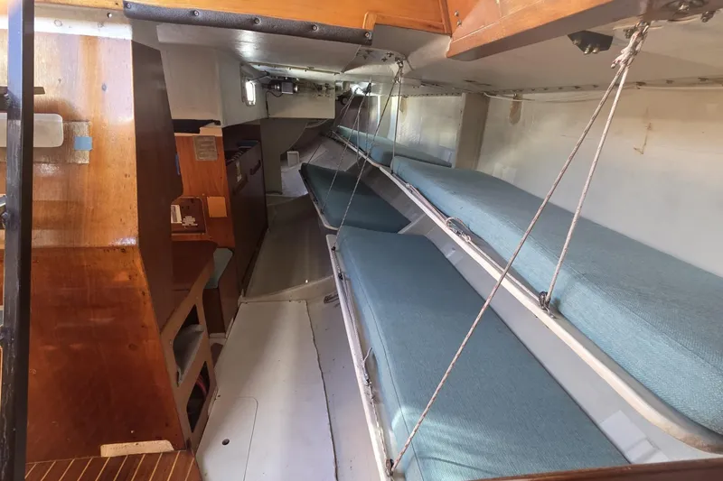 Slide: The Image of Interior of 1986 Santa Cruz 70 sailboat with wooden finishes and blue cushioned bunks. - 16