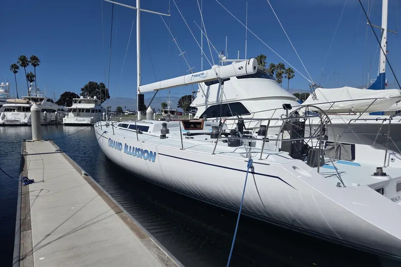 Slide: The Image of 1986 Santa Cruz 70 yacht "Grand Illusion" docked at marina, clear sky, palm trees in background. - 26