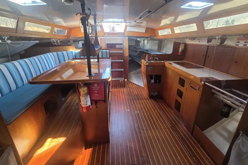 Slide: The Image of Interior of 1986 Santa Cruz 70 yacht with wooden flooring and blue-striped seating. - 4
