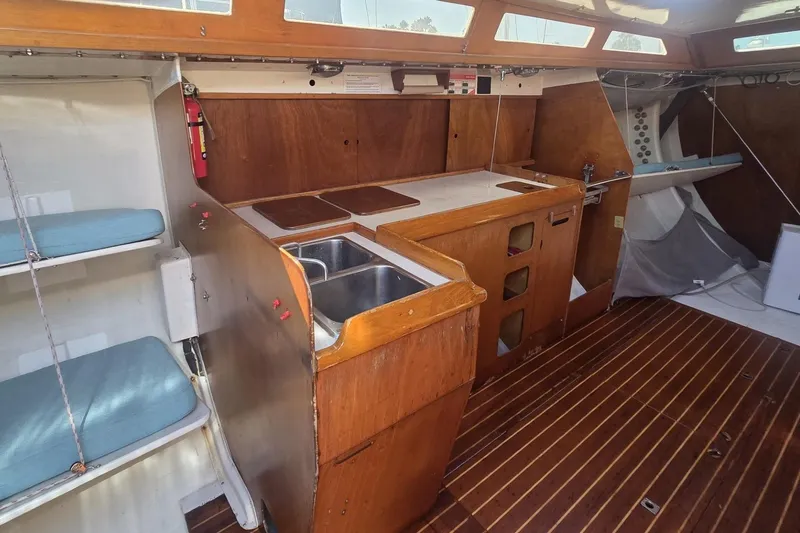 Slide: The Image of 1986 Santa Cruz 70 yacht interior with wooden cabinetry, sink, and seating area. - 5