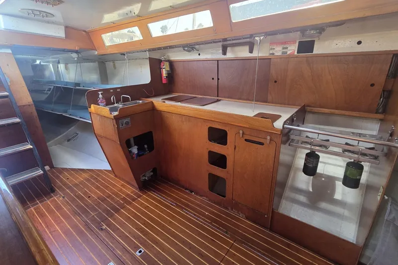 Slide: The Image of Interior of 1986 Santa Cruz 70 sailboat with wooden cabinetry and compact kitchen area. - 6