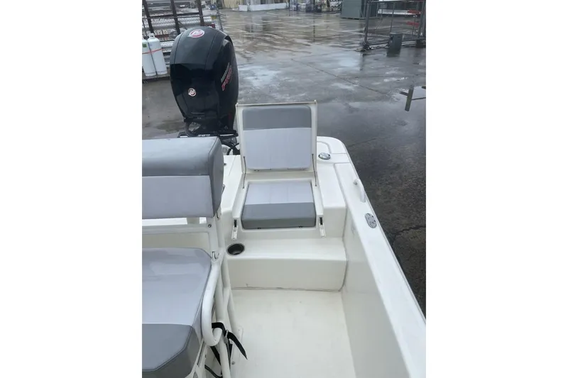 Slide: The Image of 2024 Mako Pro Skiff 19 CC boat with seating and outboard motor in a wet dock area. - 4