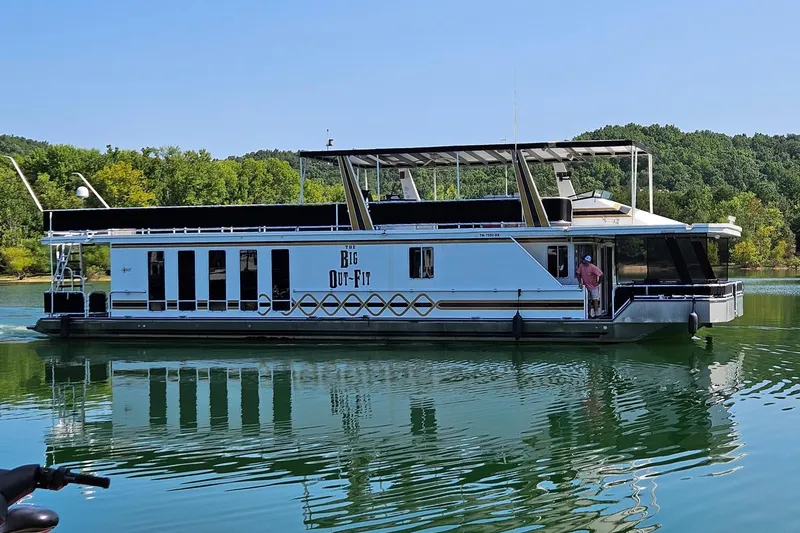 The Image of 2002 Navigator houseboat on a serene lake, surrounded by lush greenery. - 0