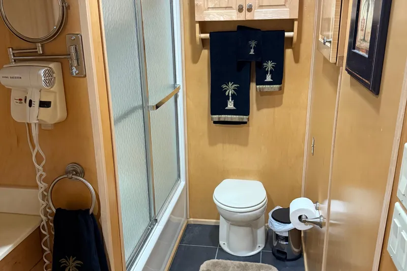 Slide: The Image of Bathroom interior of 2002 Navigator houseboat with shower, toilet, and palm-themed towels. - 13