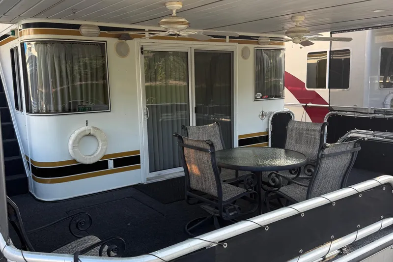 Slide: The Image of 2002 Navigator houseboat with outdoor seating, ceiling fans, and sliding glass doors. - 2