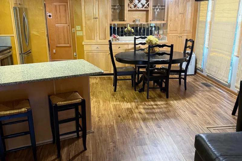 Slide: The Image of Interior of 2002 Navigator houseboat with wooden flooring, dining area, and modern kitchen. - 27