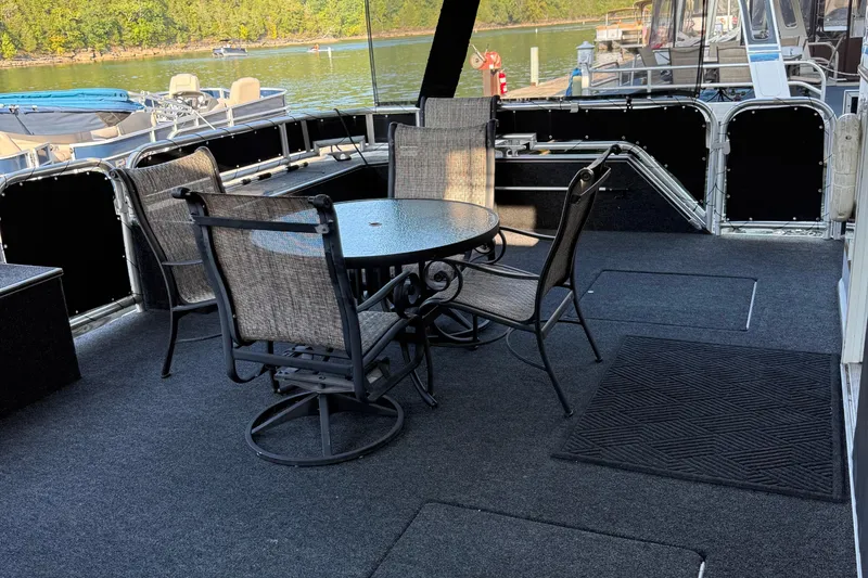 Slide: The Image of Outdoor seating area on a 2002 Navigator houseboat, featuring a round table and chairs. - 3