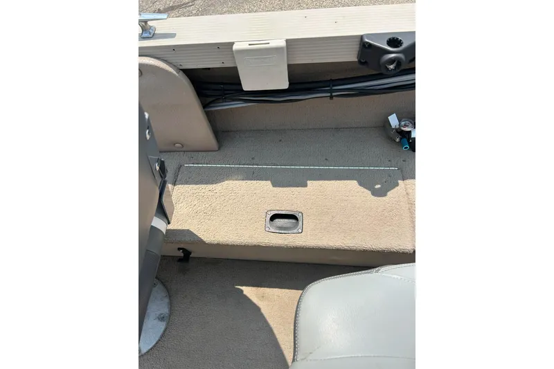 Slide: The Image of 2003 Crestliner 1850 Fish Hawk SC interior with beige carpet and storage compartment. - 16