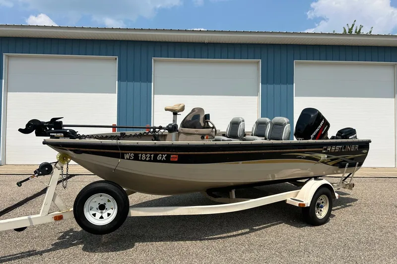 Slide: The Image of 2003 Crestliner 1850 Fish Hawk SC boat on trailer, parked in front of blue garage. - 21