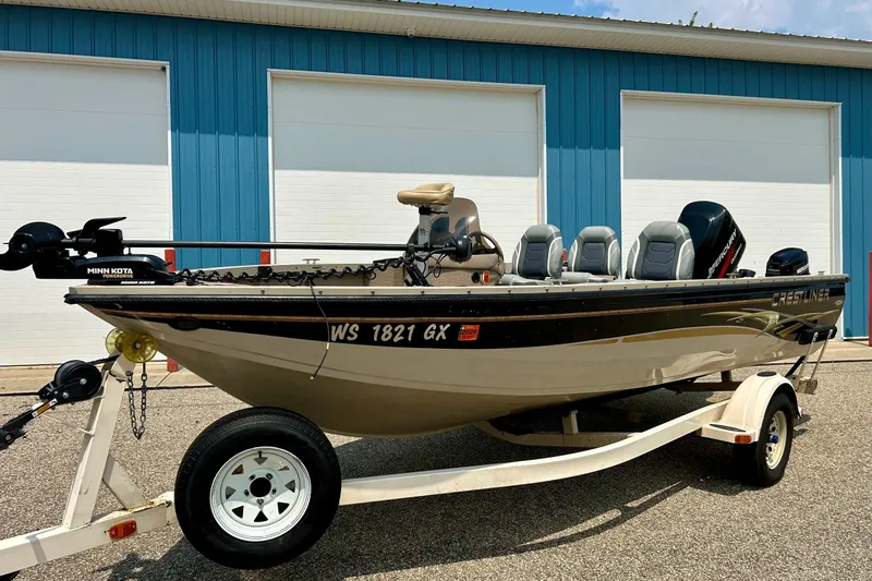 Slide: The Image of 2003 Crestliner 1850 Fish Hawk SC boat on trailer, parked outside blue building. - 22
