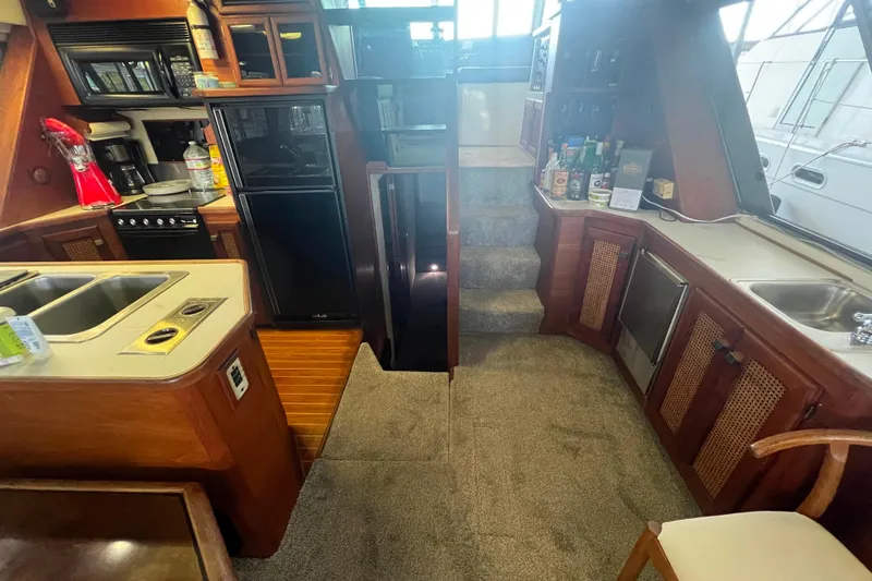Slide: The Image of Interior of 1986 Bayliner 4550 Motoryacht with kitchen and stairs, featuring wood cabinetry. - 17