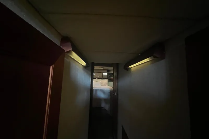 Slide: The Image of Dimly lit hallway leading to a cozy bedroom in a 1986 Bayliner 4550 Motoryacht. - 23