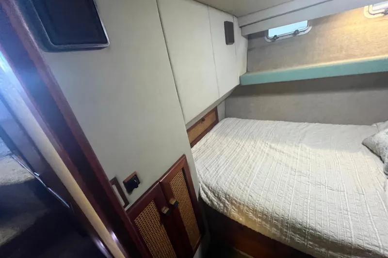 Slide: The Image of 1986 Bayliner 4550 Motoryacht cabin with bed, window, and storage cabinets. - 25