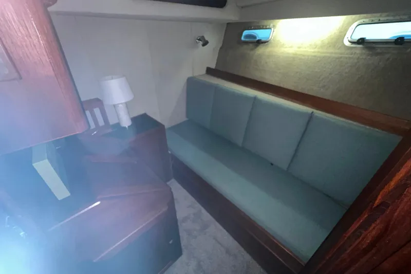 Slide: The Image of 1986 Bayliner 4550 Motoryacht interior with teal sofa, wooden accents, and soft lighting. - 27