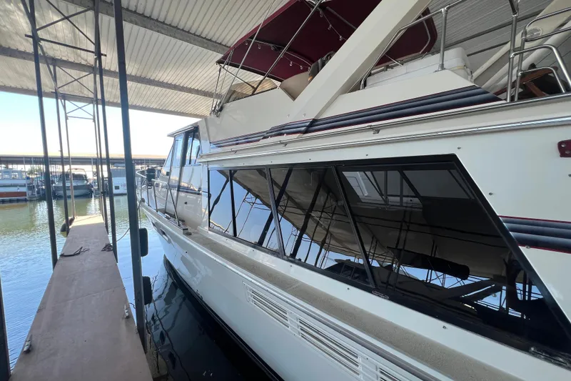 Slide: The Image of 1986 Bayliner 4550 Motoryacht docked under a covered marina. - 6
