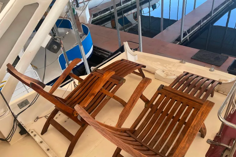 Slide: The Image of 1986 Bayliner 4550 Motoryacht deck with wooden chairs, docked at marina. - 67