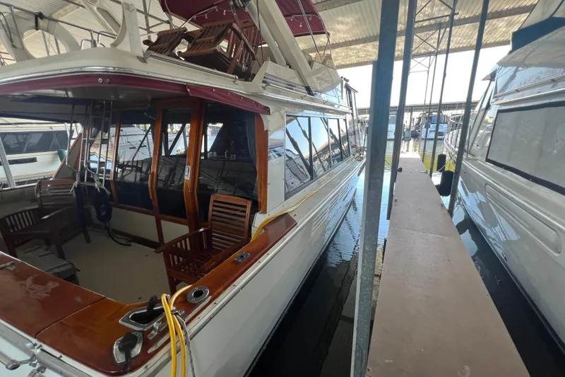 Slide: The Image of 1986 Bayliner 4550 Motoryacht docked in marina, featuring wooden deck and seating area. - 7