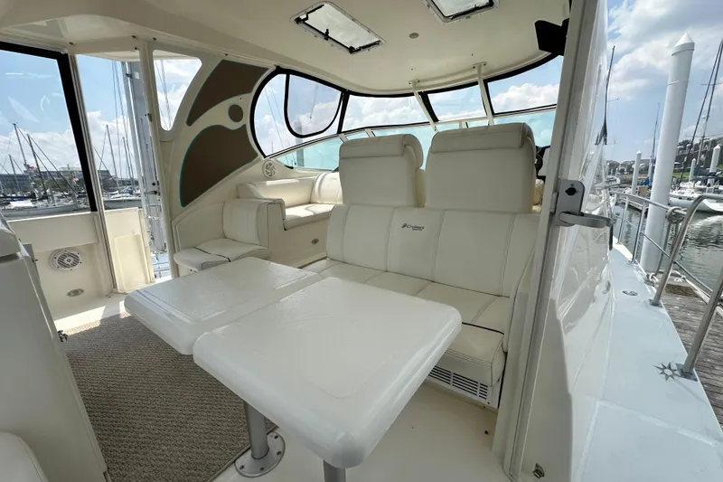Slide: The Image of 2004 Cruisers Yachts 405 Express Motoryacht interior with white seating and table, docked at marina. - 46