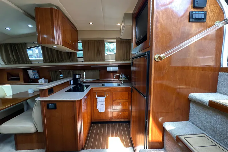 Slide: The Image of 2004 Cruisers Yachts 405 Express Motoryacht interior with wooden cabinetry and modern kitchen amenities. - 53